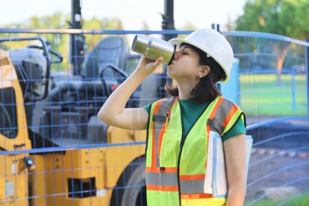 Téléchargez les photos : Portrait de femme de constructeur en plein air, travailleur de la construction ont un café boisson repos sur un lieu de travail - en image libre de droit