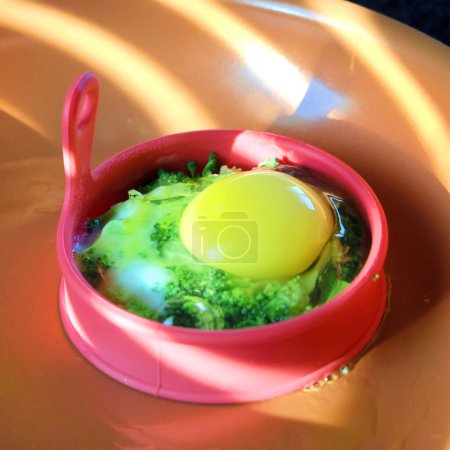 Foto de Huevo asado con brócoli en molde de silicona en una sartén, desayuno casero - Imagen libre de derechos