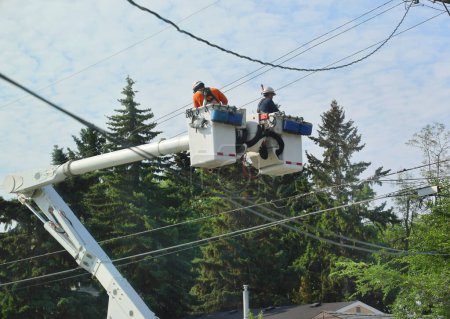 Téléchargez les photos : Deux électriciens vérifient des câbles électriques sur une grue de camion, en plein air - en image libre de droit