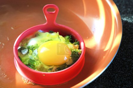 Téléchargez les photos : Œuf rôti au brocoli dans un moule en silicone sur une poêle en céramique, petit déjeuner maison sain - en image libre de droit