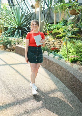 Téléchargez les photos : Jeune étudiante botaniste marchant dans un jardin botanique - en image libre de droit