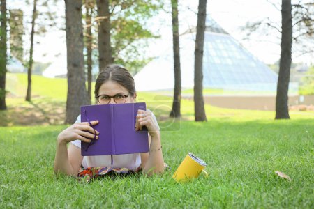 Photo for Happy student woman take a rest in a park reading a book on a grass - Royalty Free Image
