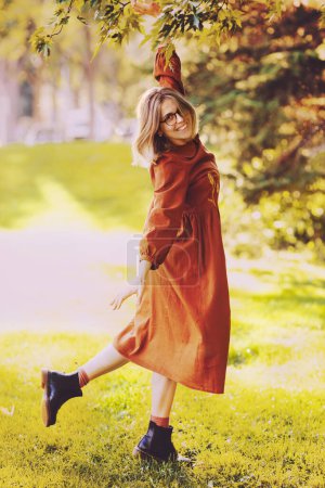 Téléchargez les photos : Belle jeune femme ont un loisir dansant dans le parc d'automne habillé en robe brune longue - en image libre de droit