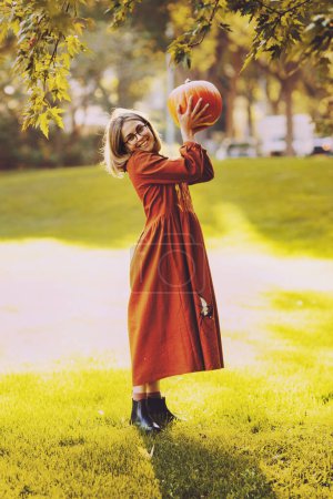 Téléchargez les photos : Belle jeune femme ont un loisir debout avec citrouille dans les mains dans le parc d'automne - en image libre de droit