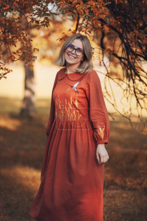 Téléchargez les photos : Belle jeune femme ont un loisir de marche dans le parc d'automne vêtu de longue robe brune - en image libre de droit