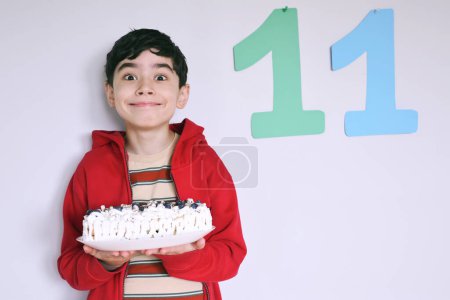Téléchargez les photos : Garçon mignon tenant tarte aux myrtilles maison avec crème blanche - en image libre de droit