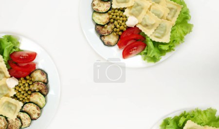 Foto de Fondo blanco con platos veganos con deliciosos ravioles y verduras - Imagen libre de derechos