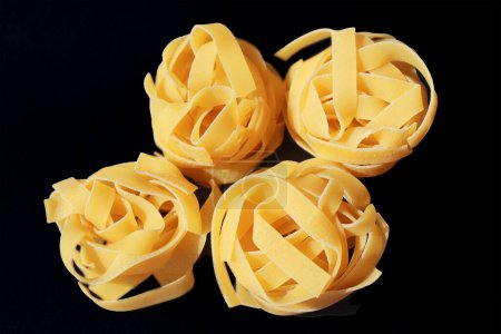 Photo for Italian rolled raw fettuccine pasta  on the black  background. - Royalty Free Image