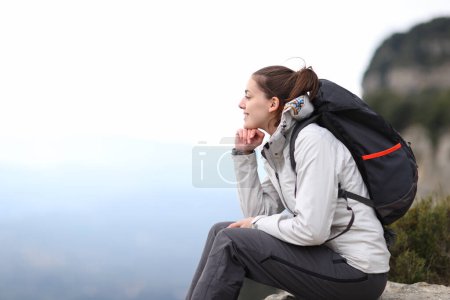 Photo for Side view portrait of a hiker contemplating mountain views from a cliff - Royalty Free Image