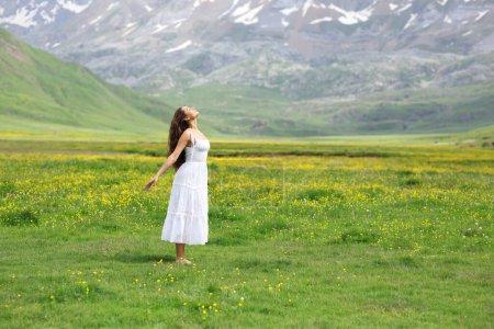 Retrato de una mujer con vestido blanco respirando aire fresco en la montaña