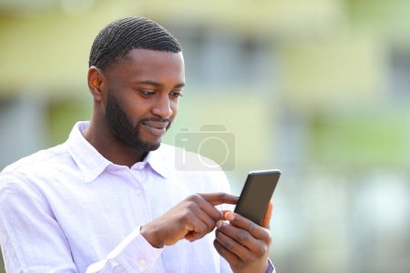 Photo for Black man browsing content on smart phone in the street - Royalty Free Image