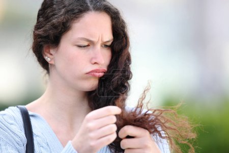 Photo for Angry woman cheking hair split ends in the street - Royalty Free Image