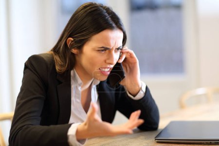 Empresaria enojada hablando por teléfono quejándose en la oficina