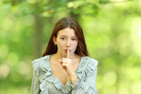 Photo for Front view portrait of a woman who is asking for silence in a forest - Royalty Free Image