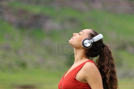 Téléchargez les photos : Side view portrait of a woman meditating listening audio guide in nature - en image libre de droit