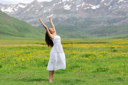 Photo for Excited woman in white dress raising arms in nature - Royalty Free Image