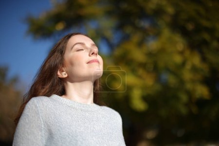 Relaxed woman breathing fresh air in nature a sunny day