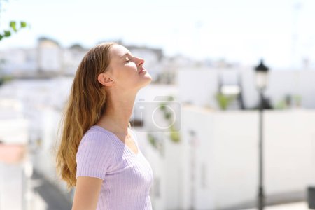 Téléchargez les photos : Femme détendue respirant l'air frais en vacances d'été dans une ville blanche espagnole - en image libre de droit