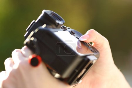 Téléchargez les photos : Gros plan d'une caméra sans miroir mise à la main par un photographe dans un parc - en image libre de droit