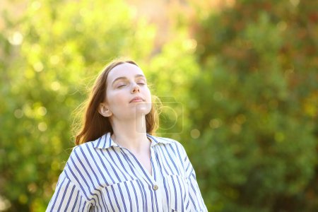 Elegant woman breathing fresh air standing in a park