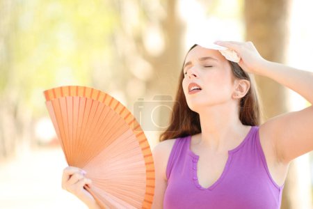 Téléchargez les photos : Femme stressée séchant la sueur avec un tissu et ventilant une chaude journée d'été - en image libre de droit