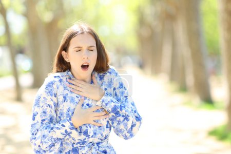 Photo for Front view portrait of a stressed woman choking in a park - Royalty Free Image