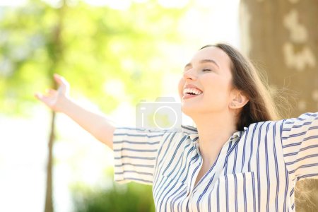 Excited and happy woman outstretching arms in nature