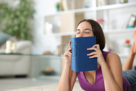 Reader smelling paper book lying on the floor at home