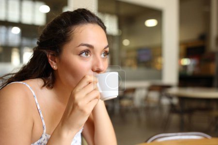 Téléchargez les photos : Femme sirotant du café assis dans un bar intérieur - en image libre de droit