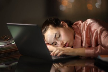Foto de Empresario sobrecargado que duerme encima del ordenador portátil en la noche en oficina o en casa - Imagen libre de derechos