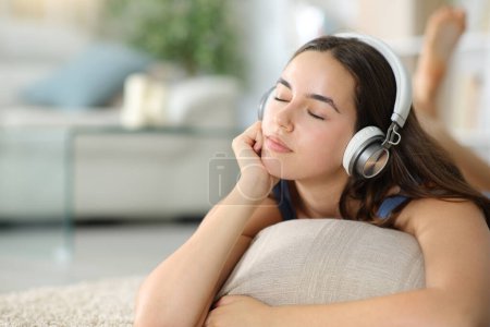 Photo for Relaxed woman wearing headphone listening chill music on the floor at home - Royalty Free Image