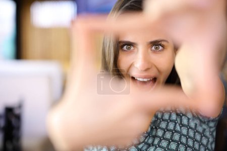 Happy woman framing with her hands looking at you in a bar
