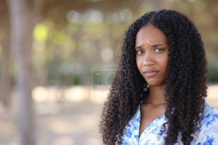 Disappointed black woman looking at camera standing in a park