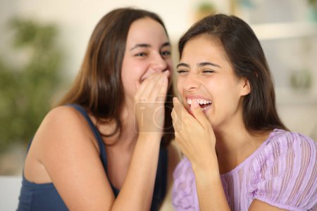 Happy gossip girls telling secrets and laughing at home