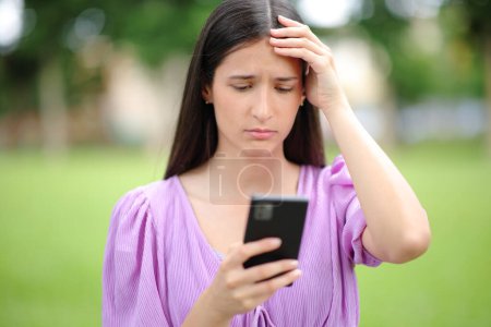 Foto de Retrato de una mujer preocupada revisando malas noticias en un teléfono inteligente en un parque - Imagen libre de derechos