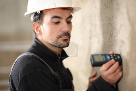 Construction worker using a digital distance meter in a wall