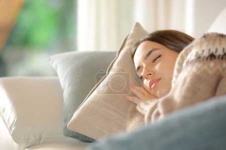 Mujer durmiendo profundamente tumbada en un sofá en casa
