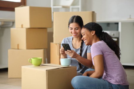Noir et blanc femmes vérifier téléphone déménagement maison dans la cuisine