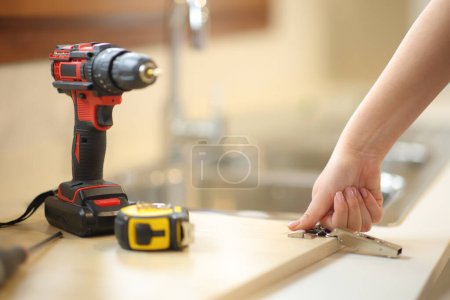 Woman hand assembling kitchen furniture in the kitchen at home