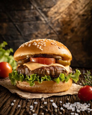 Homemade hamburger with fresh vegetables on rustic wooden background.