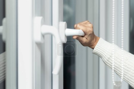 Foto de Primer plano de una mano de mujer abre una ventana blanca de plástico para ventilar. - Imagen libre de derechos