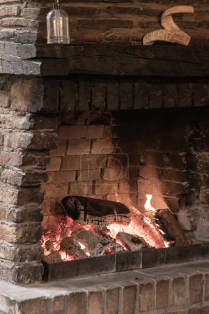Téléchargez les photos : Charme rustique : une cheminée confortable illumine un intérieur de pays - en image libre de droit