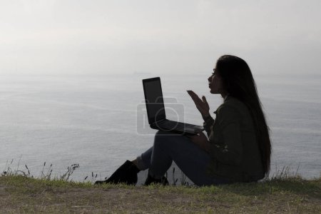 Téléchargez les photos : Paradis : Belle femme engagée dans une réunion virtuelle au milieu de la tranquillité en bord de mer - en image libre de droit