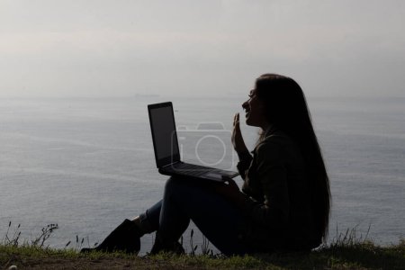 Téléchargez les photos : Tranquille soirée en tant que femme brune s'engage dans un appel vidéo pour ordinateur portable - en image libre de droit