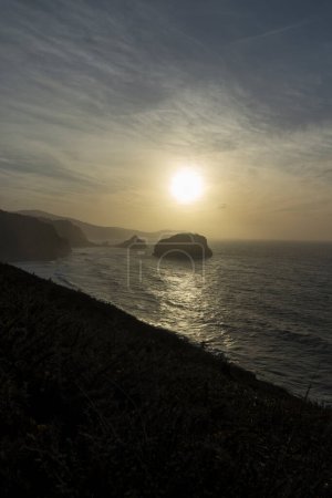 Foto de El encanto de la belleza costera de Gaztelugatxe bajo el sol poniente - Imagen libre de derechos