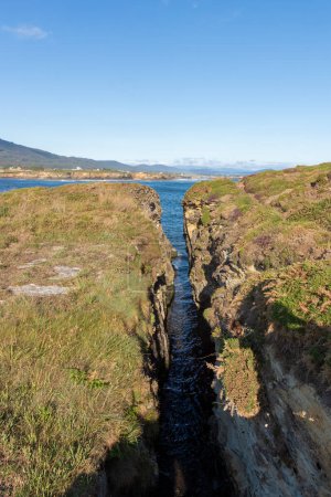Téléchargez les photos : Paysage naturel serein avec un canal d'eau étroit menant à un plus grand plan d'eau sous un ciel clair - en image libre de droit