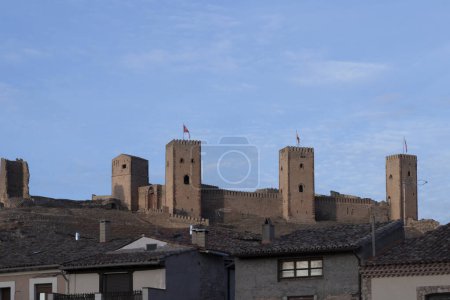 ancient castle with tall towers overlooks a modern town, showcasing architectural contrast and historical preservation