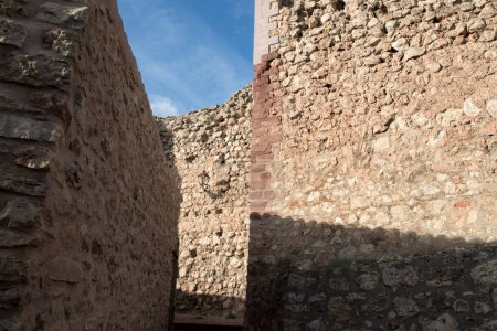 paredes de piedra bajo un cielo despejado, creando un camino estrecho, mostrando textura e historia en un ambiente sereno.