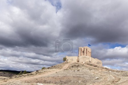 alter Steinturm mit Fahne, mit Blick auf eine malerische Stadt inmitten der Natur, unter wolkenverhangenem Himmel