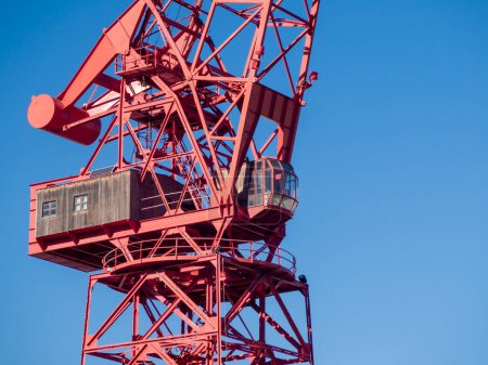 red crane against a clear blue sky, highlighting industrial design and engineering against nature's backdrop